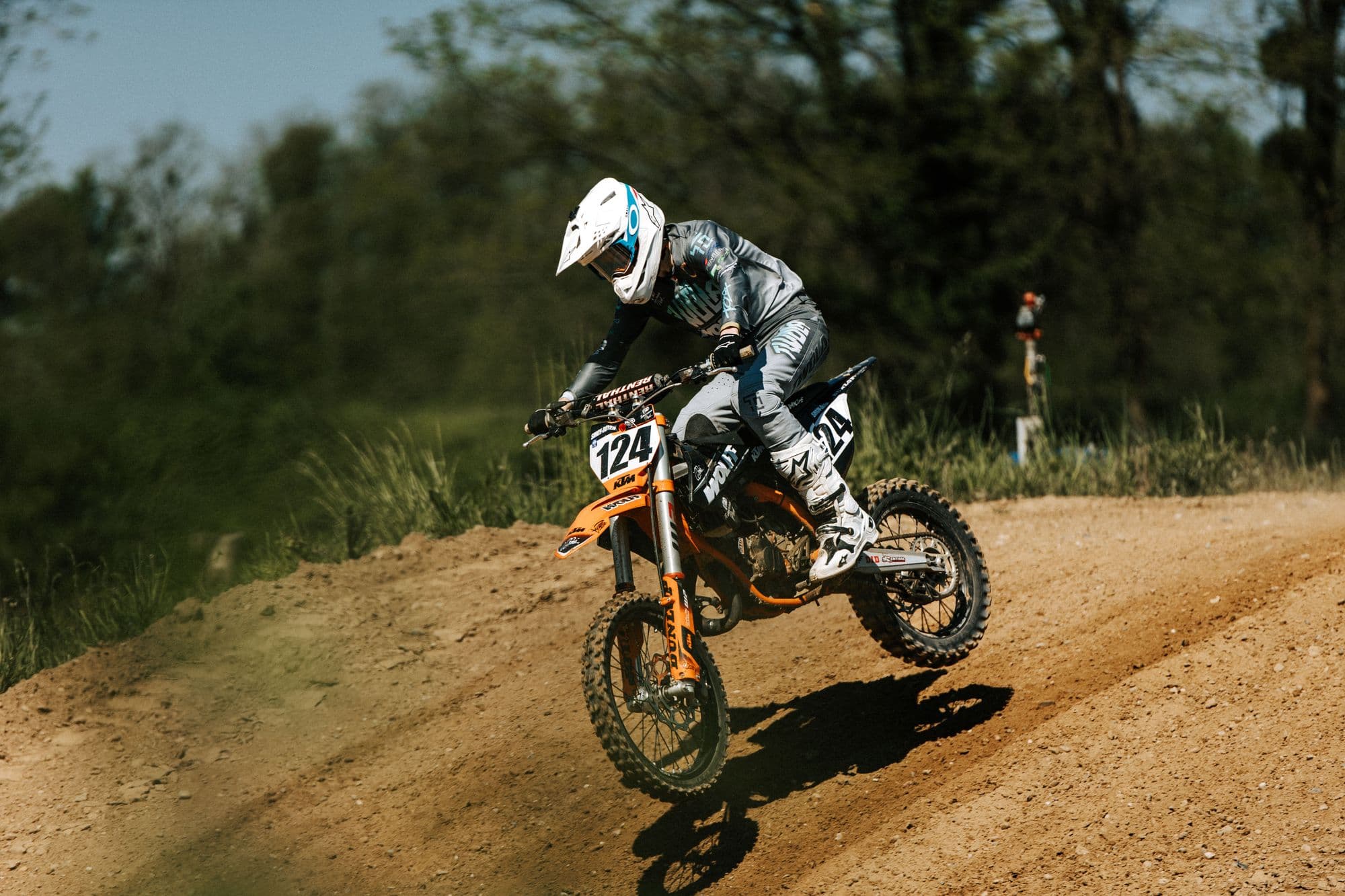 Motocross rider in full kit powering over a dirt rise