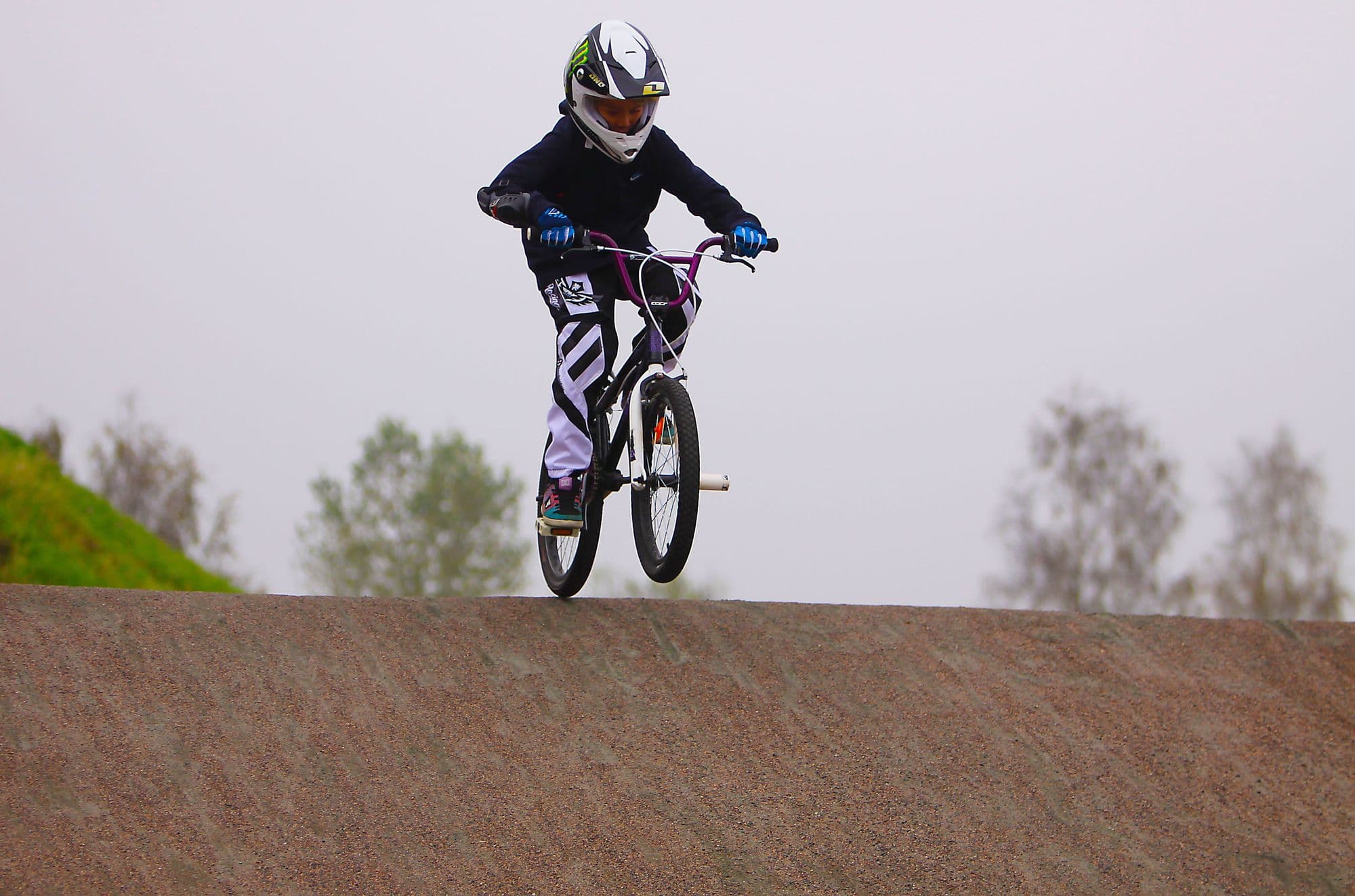 BMX racer airborne over a track jump against the sky