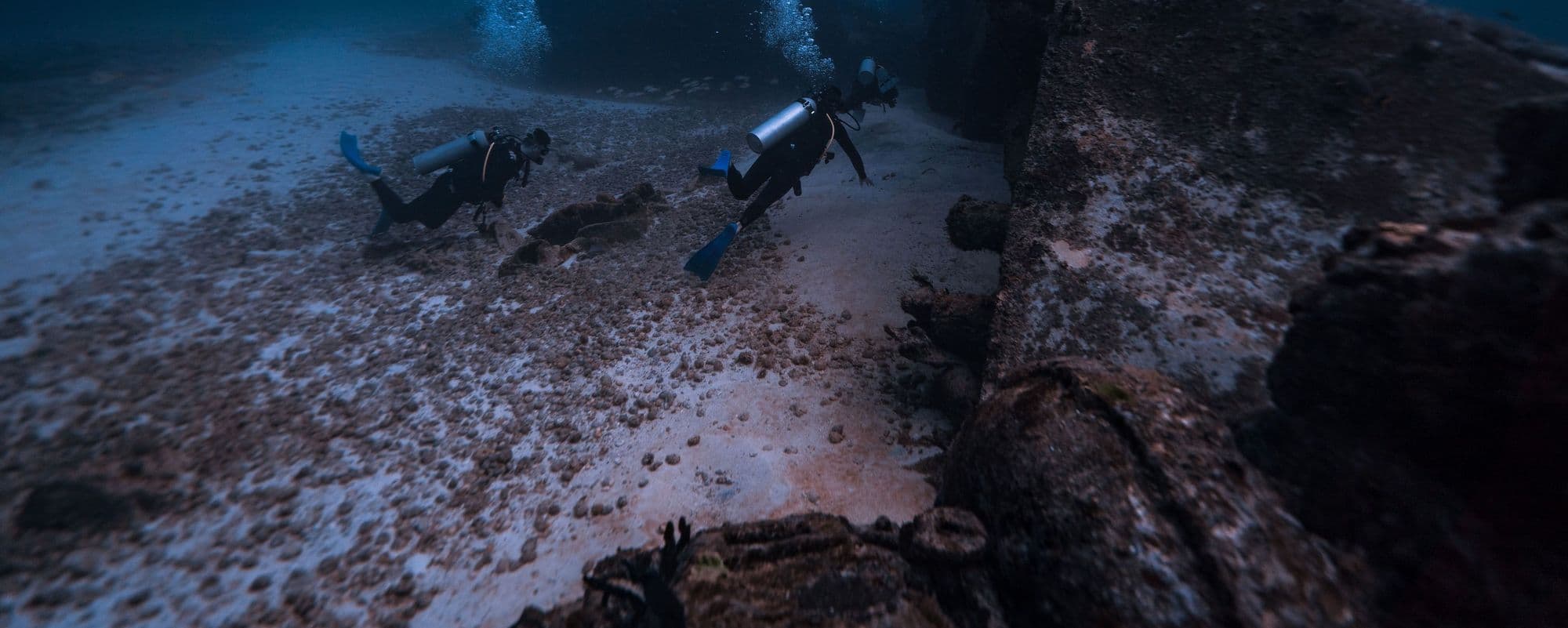 Two scuba divers exploring a shipwreck on the seabed