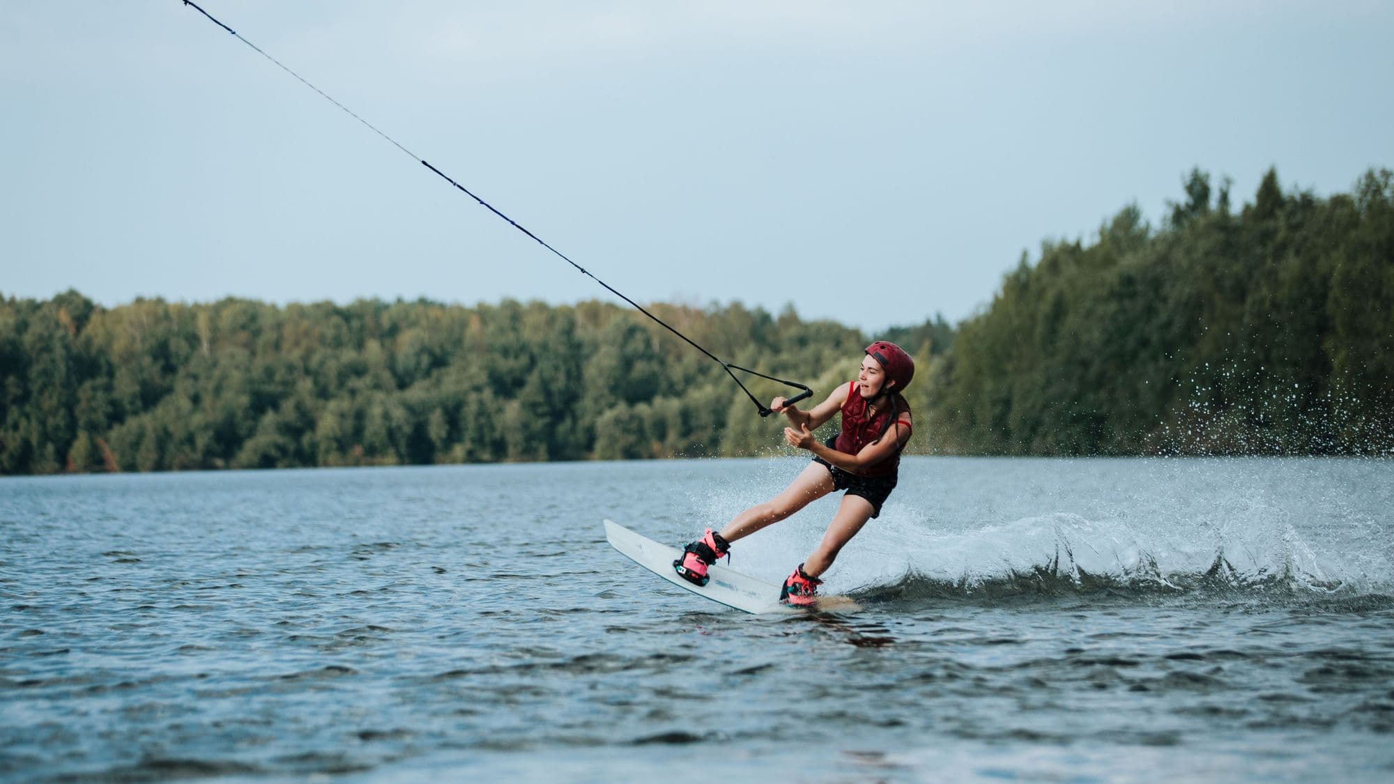 Wakeboarder carving behind the overhead cable line on a lake