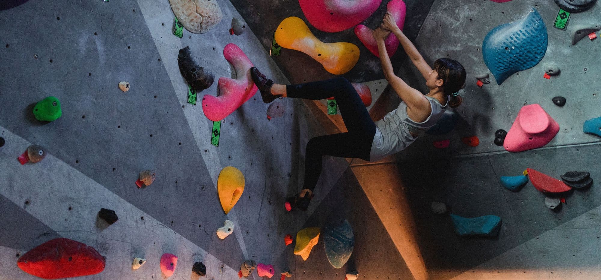 Climber bouldering on colourful holds at an indoor wall