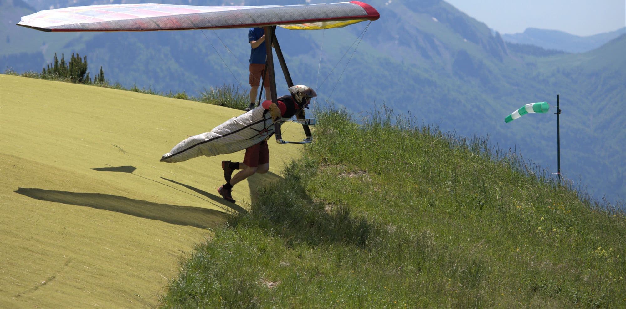 Hang glider pilot in helmet and harness running a launch