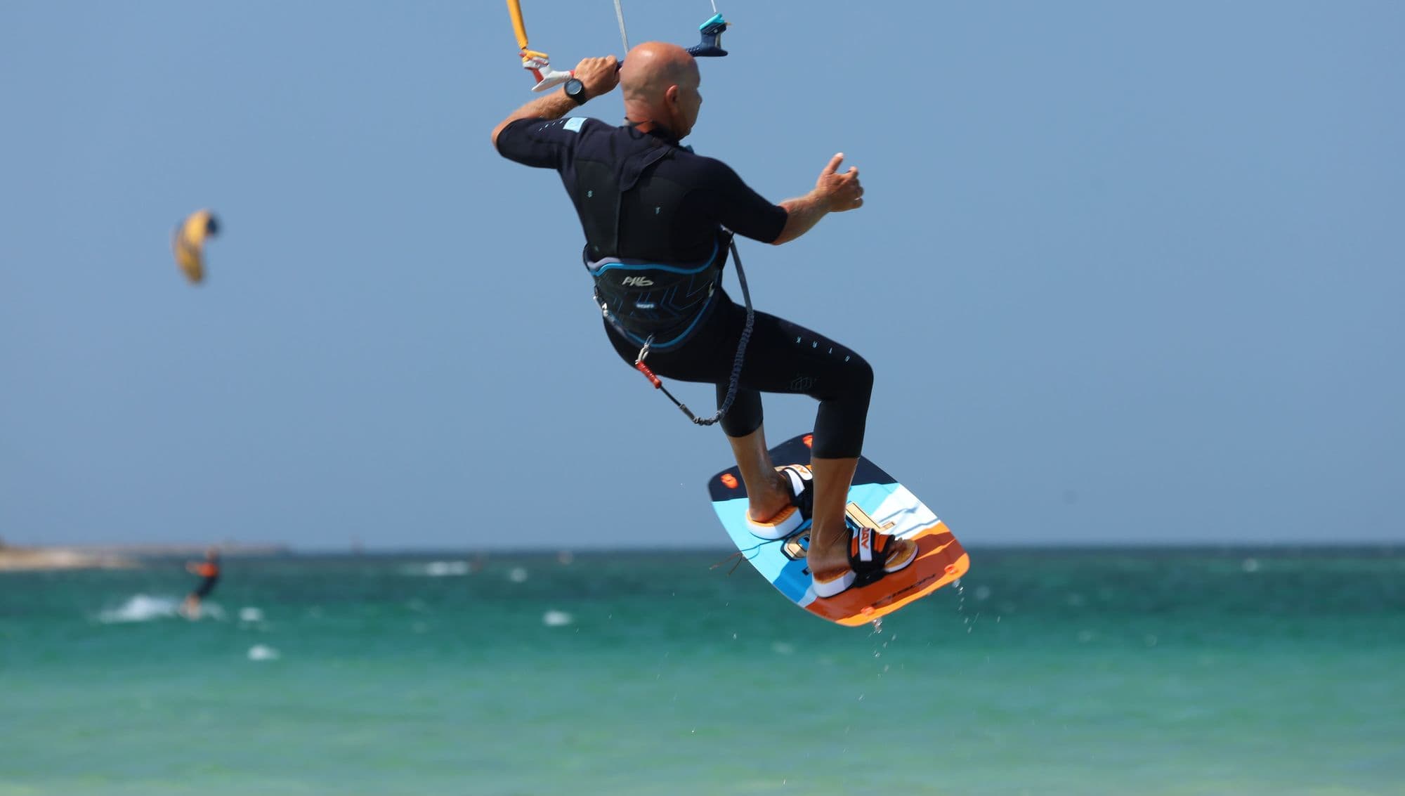 A kitesurfer boosting a jump above turquoise water