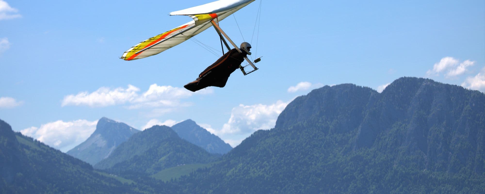 Hang glider soaring high above green mountains