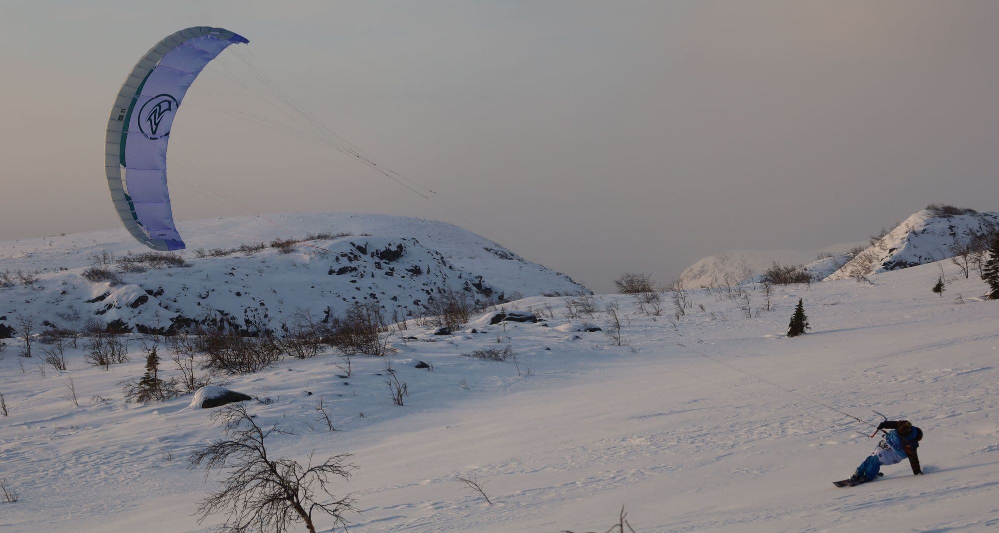 A rider on snowy open ground powered by a large traction kite