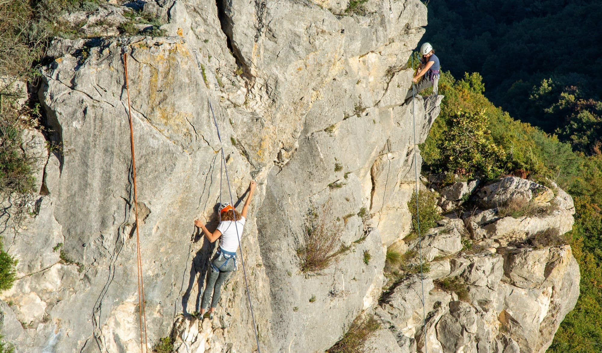 Climber leading up a vertical limestone crag