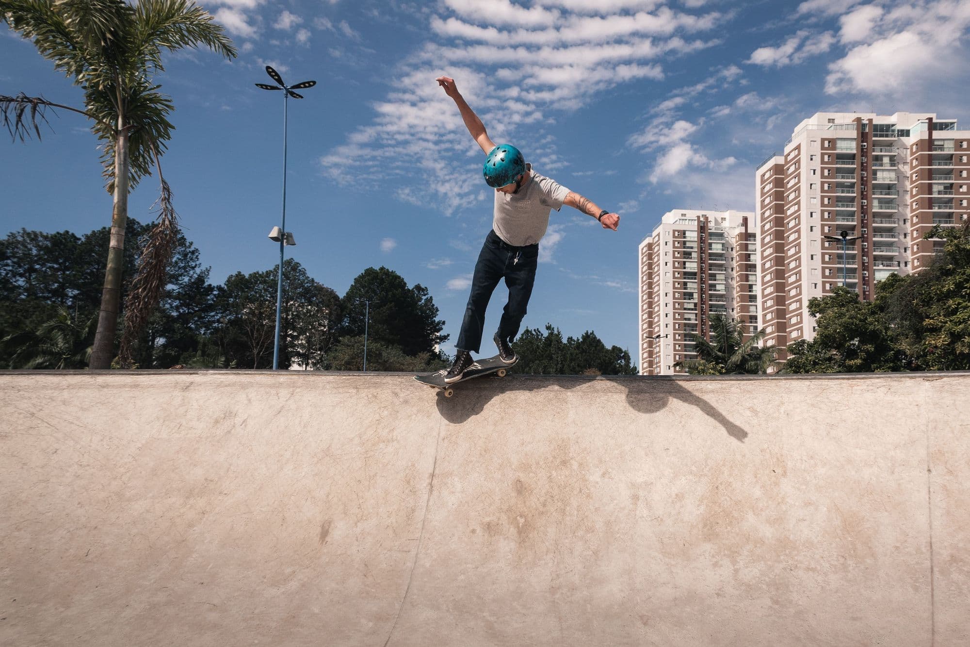 Skater in a helmet standing on the coping ready to drop in, under a bright blue sky