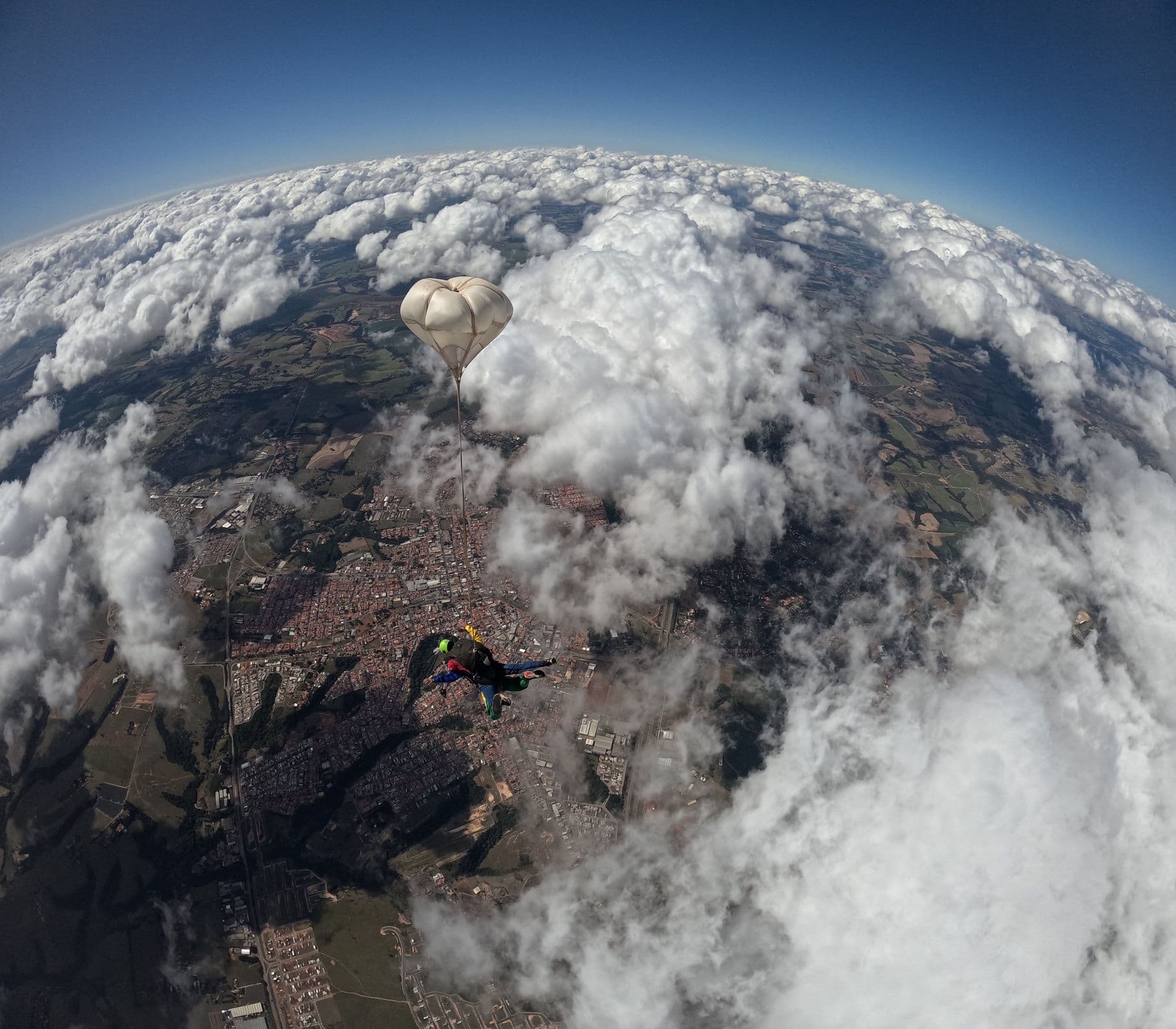 Skydiver under canopy high above a sea of clouds