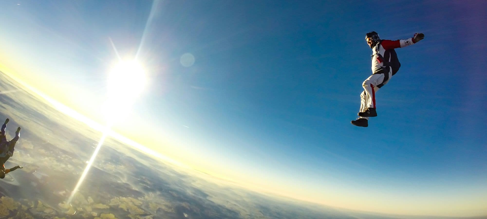 Freeflyer in a sit position in freefall, with the sun low on the horizon