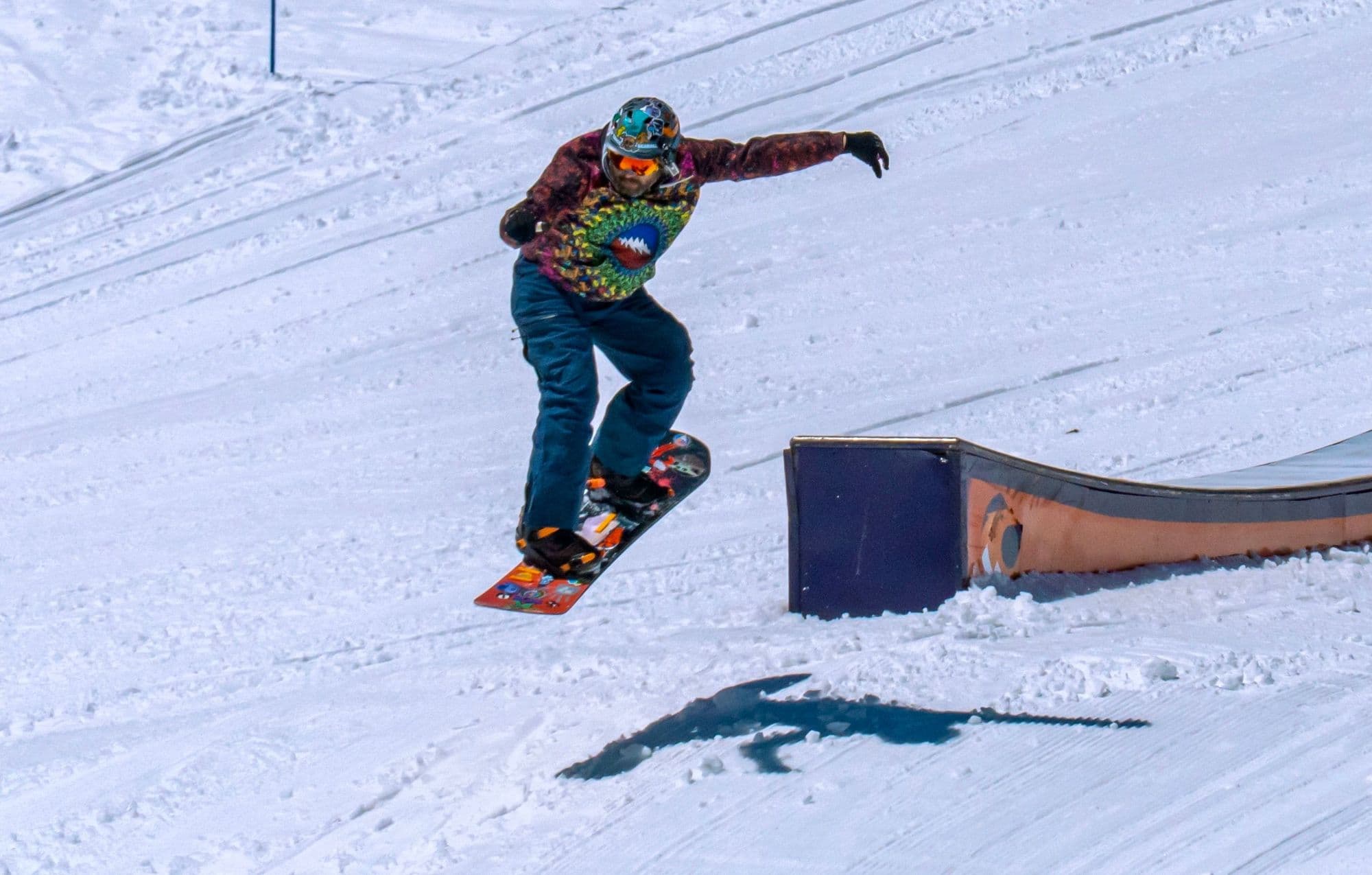 A snowboarder sliding a rail in a snowy terrain park at Lake Tahoe