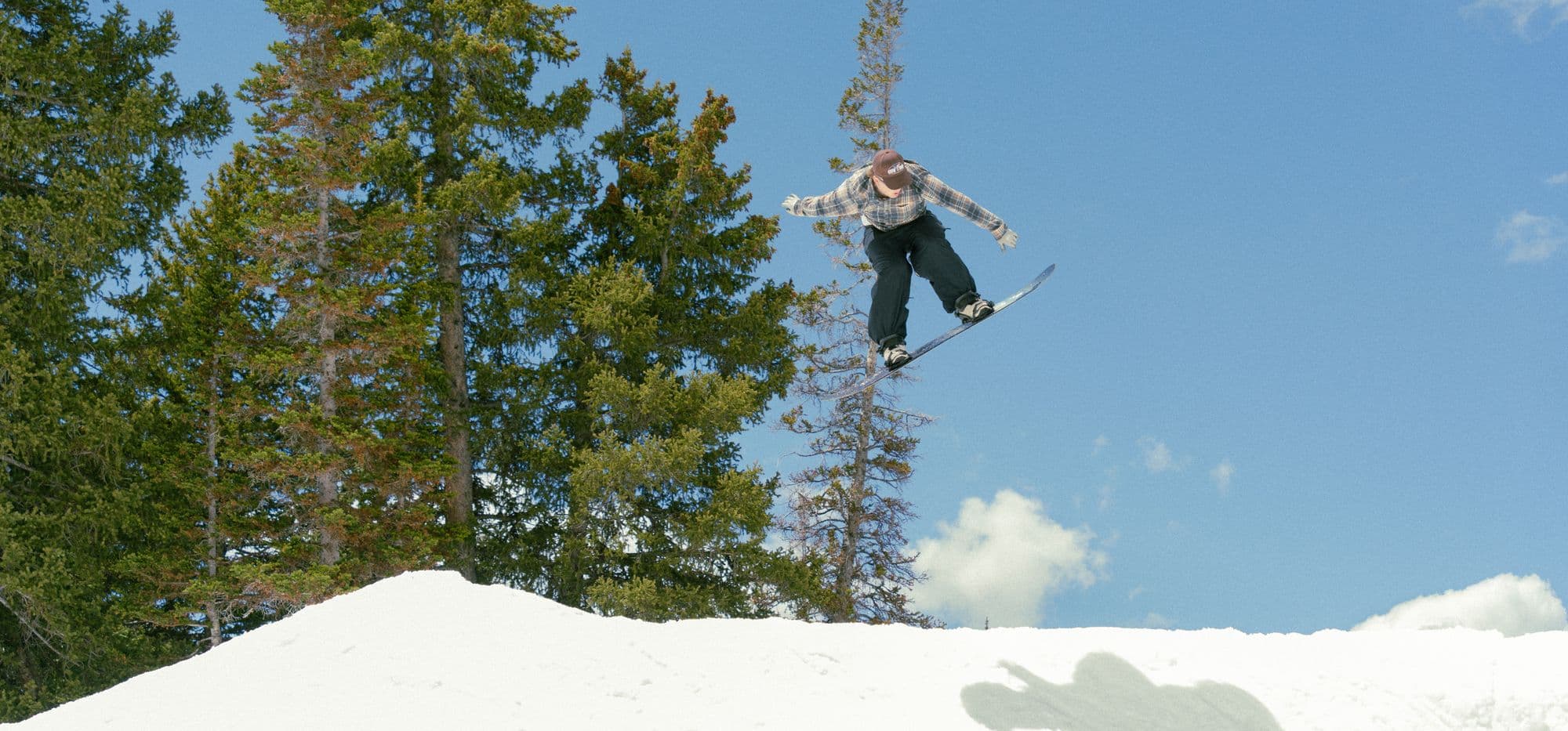 A snowboarder mid-air against a clear blue sky at Brighton Resort, Utah
